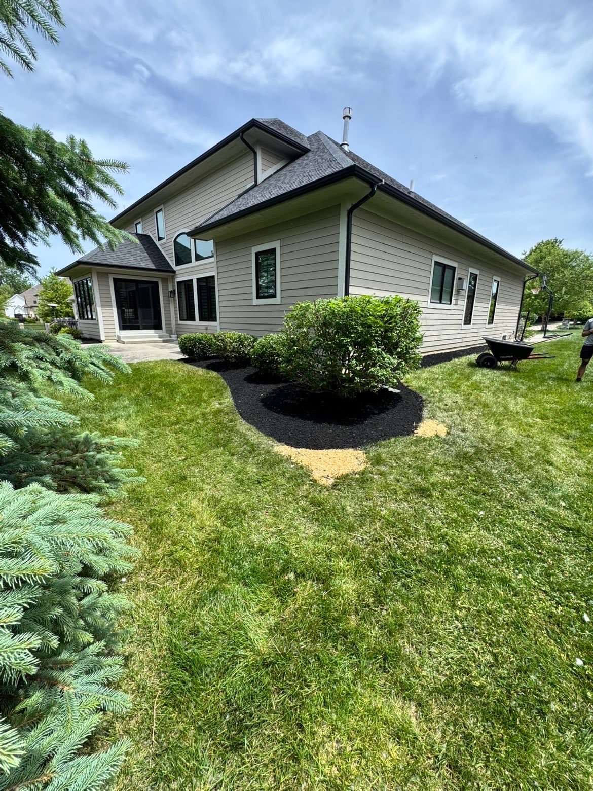Fresh black mulch beds wrapping the side of a large home