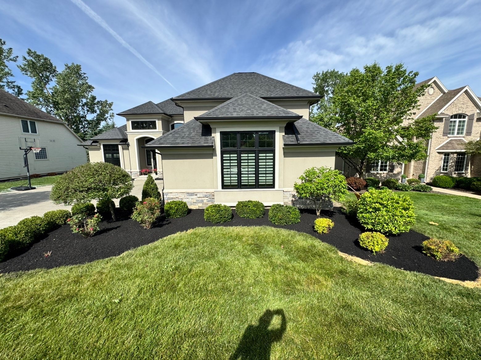 Manicured lawn and fresh mulch beds wrapping a Monclova home
